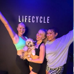 Riders with the LIFE CYCLE wall and a studio pup